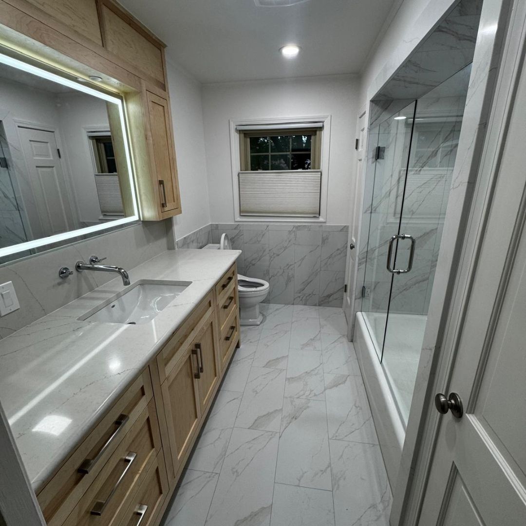 Bathroom remodel with lit mirror and marble shower